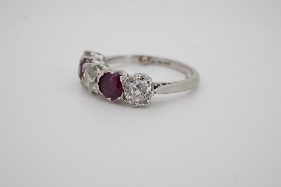 A ruby and diamond five-stone ring, set with an alternating sequence of antique cushion-shaped diamonds totalling approximately 1.50 carats, spaced with circular-cut rubies, mounted in platinum, size M (sizing beads), Br